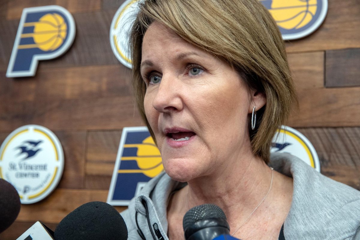 Kelly Krauskopf speaks into microphones in front of a Pacers backdrop.