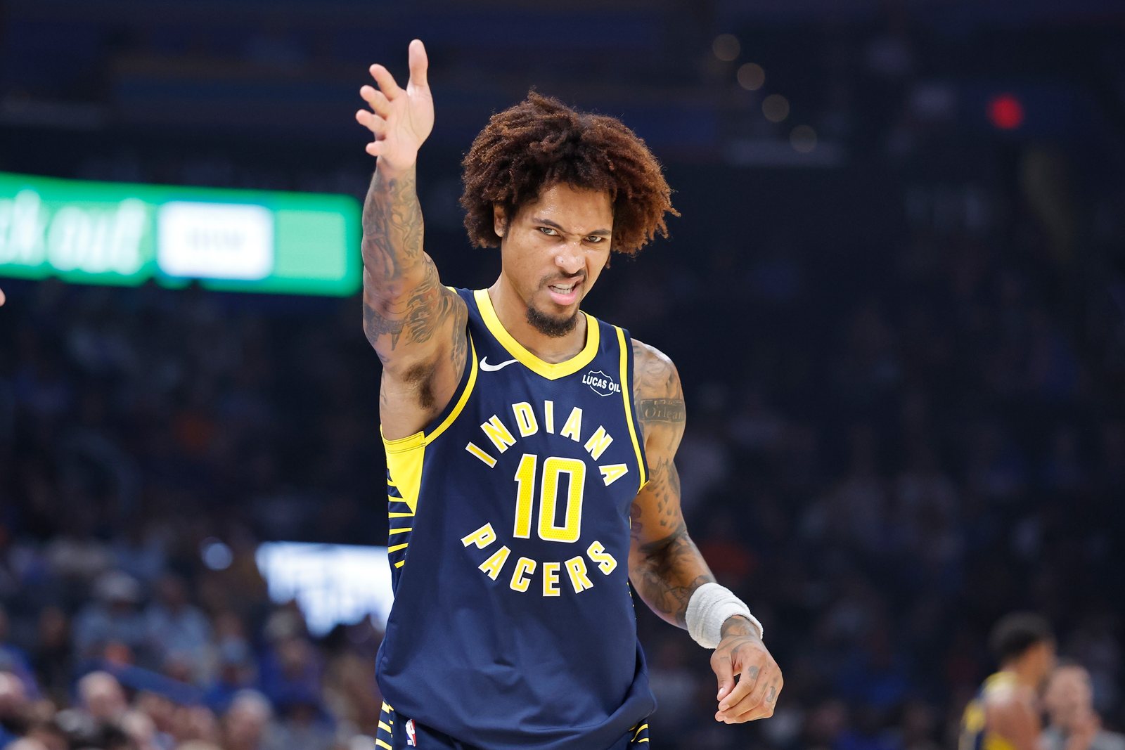 Kelly Oubre Jr. in a navy Pacers jersey raises his right hand after a play against the Thunder in Oklahoma City.
